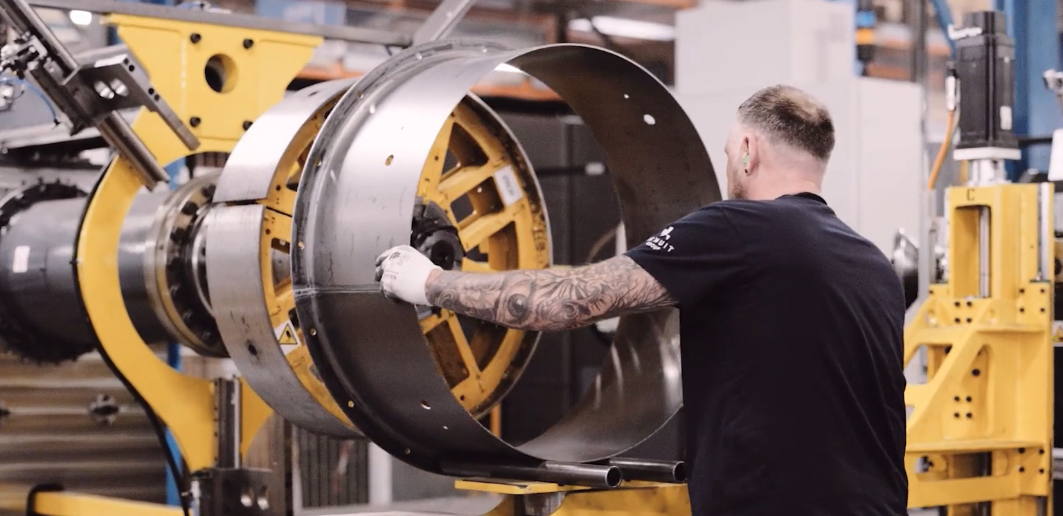 image of a man pushing metal fan plate into machine