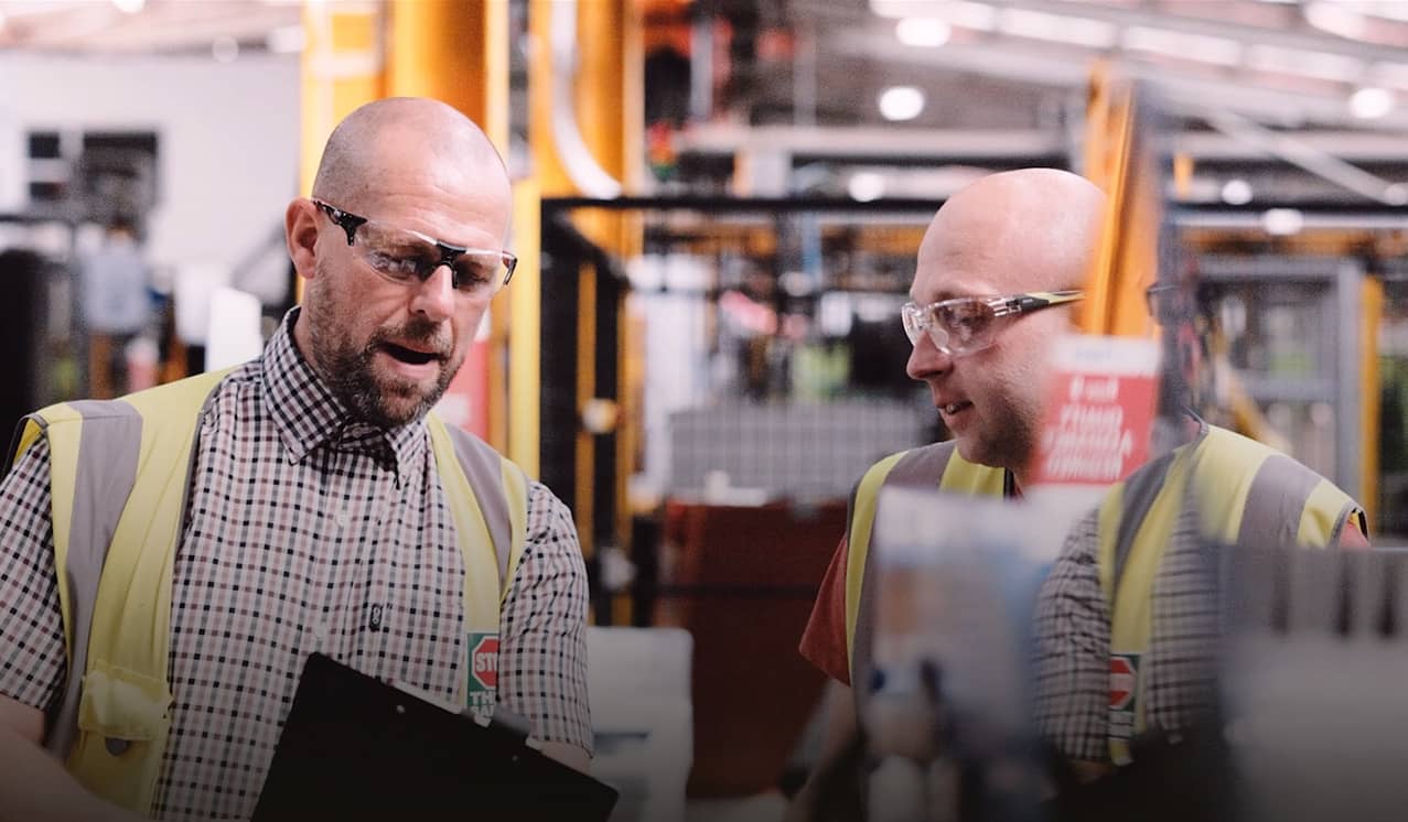 Two engineers observe a clipboard.